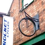 Halbes altes Fahrrad haengt an der Wand vor einem Fahrradladen